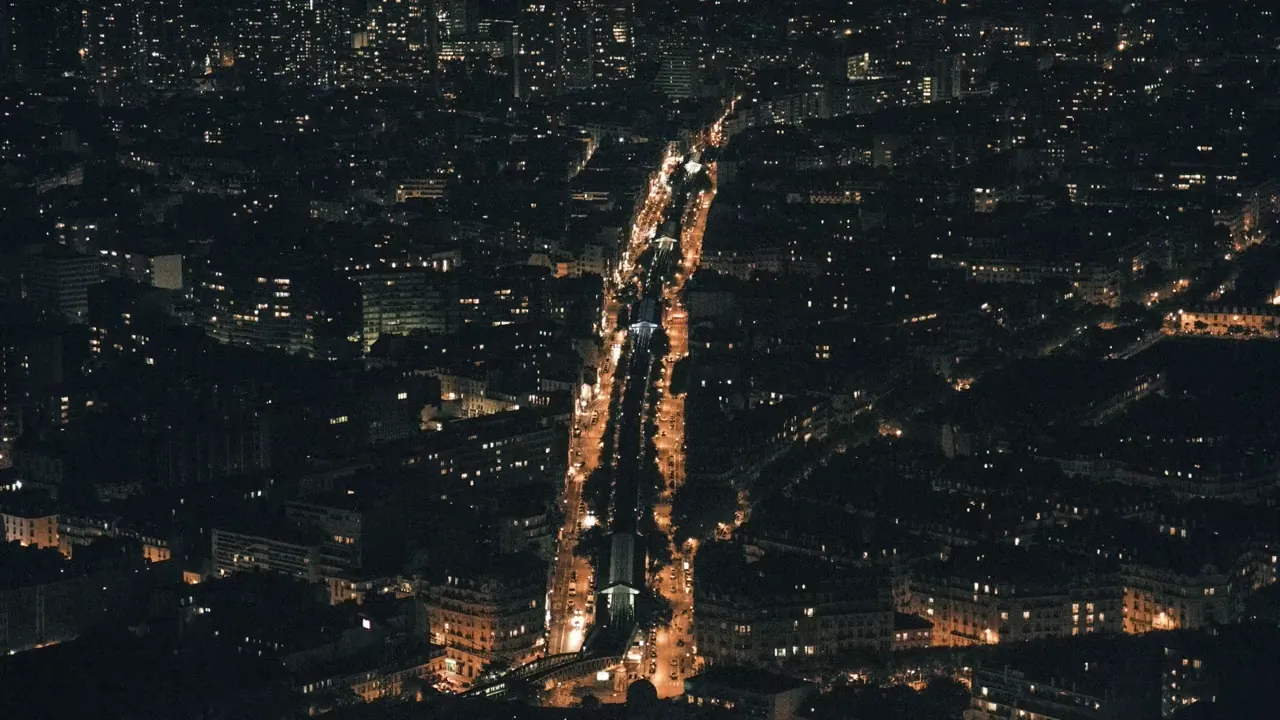 A city at night seen from above, streets drawn in light
